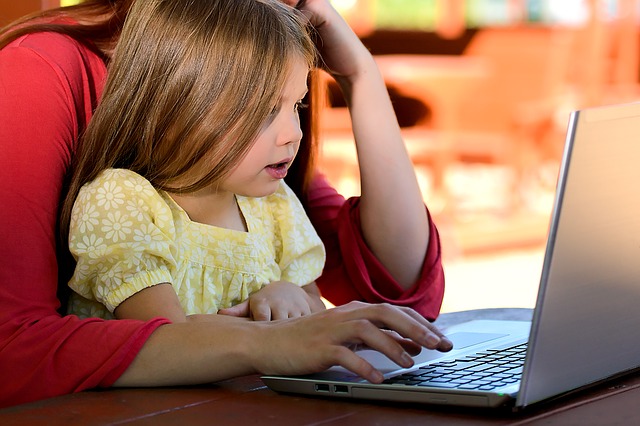 child on mother's lap looking at laptop computer